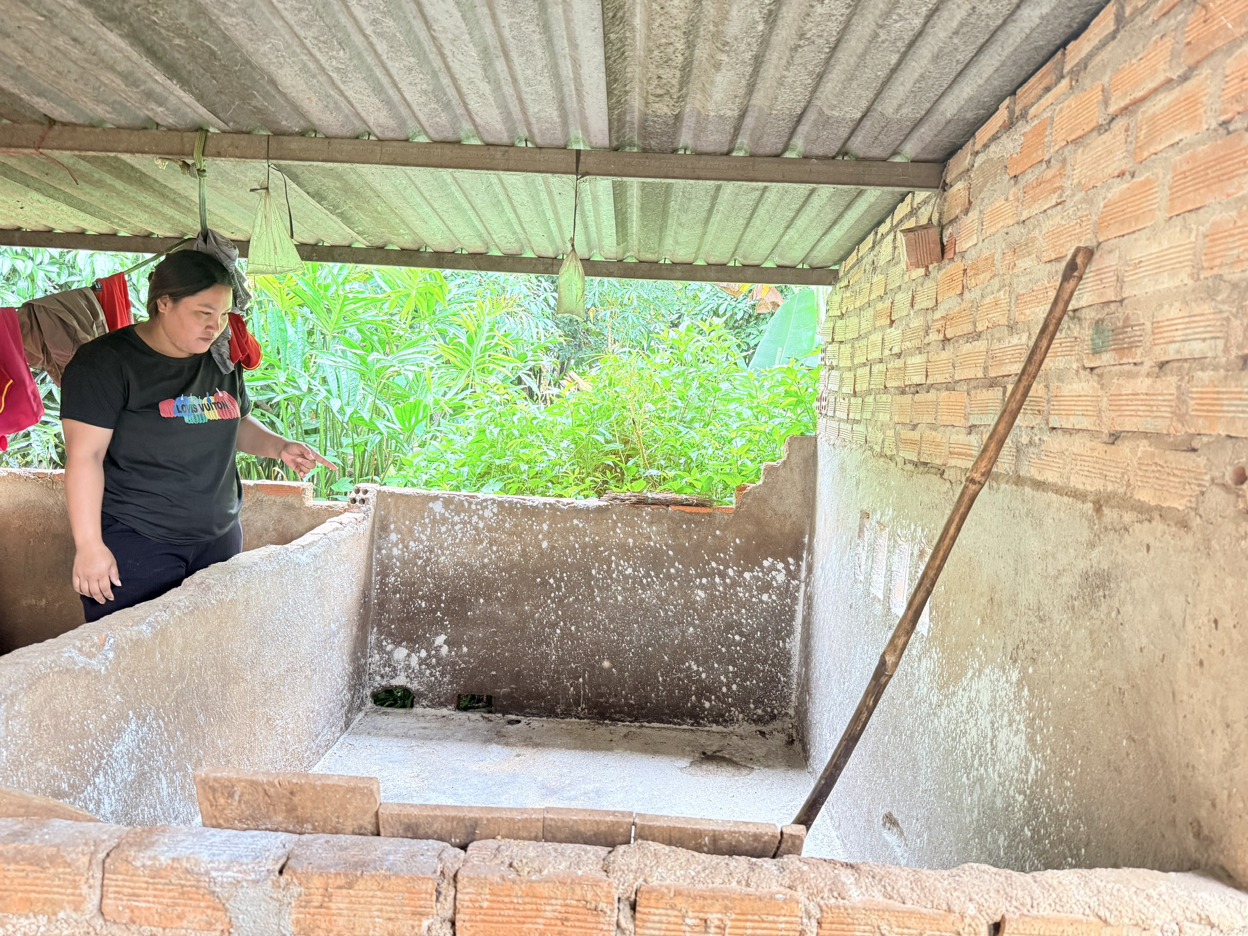 Chị H Doăn Niê bên khu chuồng nuôi trống trơn của gia đình